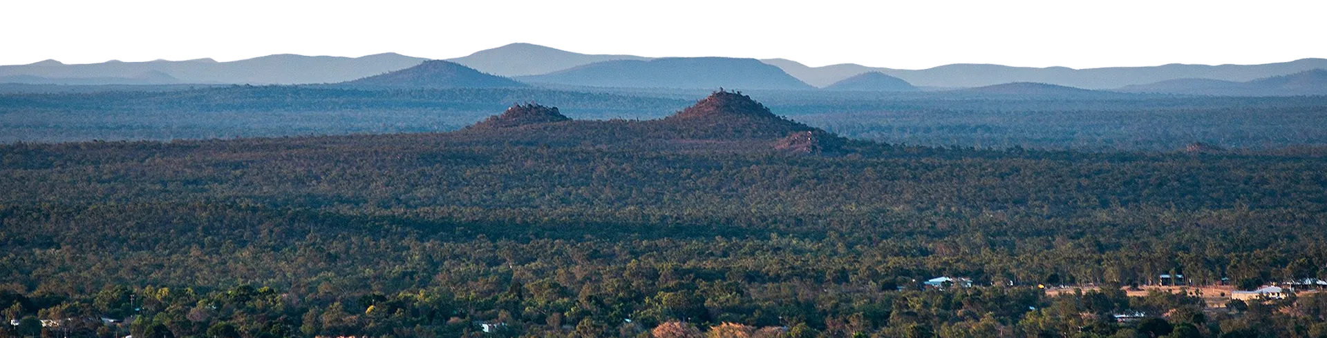 Aerial view of a small North Queensland town among forested volcanic plains and distant hills at dusk